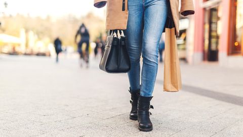 Eine Frau in Jeans geht über eine Straße