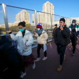 In Peking eilen Menschen auf dem Weg zur Arbeit über einer Fußgängerbrücke.