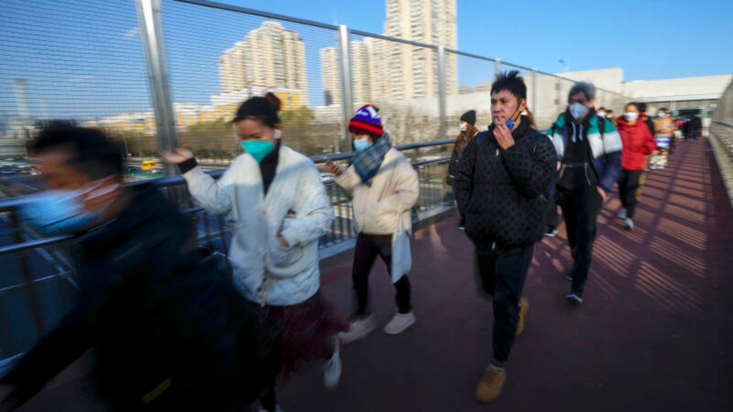 In Peking eilen Menschen auf dem Weg zur Arbeit über einer Fußgängerbrücke.