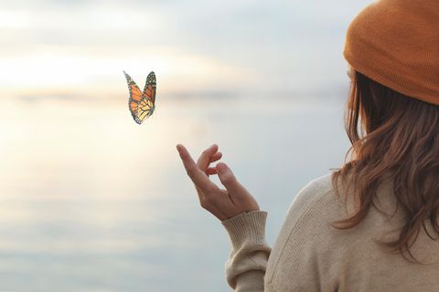 Eine Frau lässt einen Schmetterling auf ihrem Finger landen