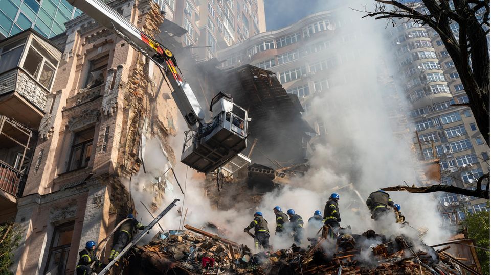Feuerwehrleute arbeiten nach dem Beschuss auf Gebäude durch eine Drohne