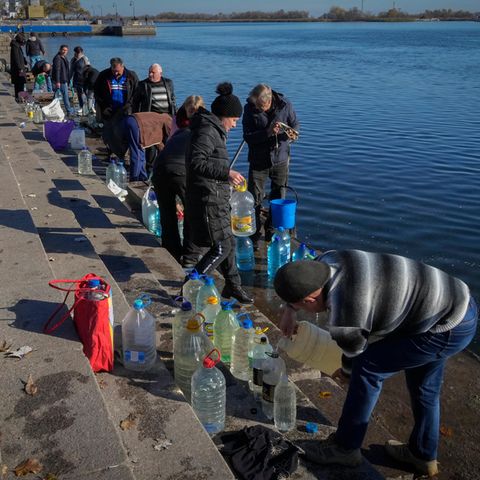 Menschen füllen Wasser aus dem Fluss Dnipro in Kanister