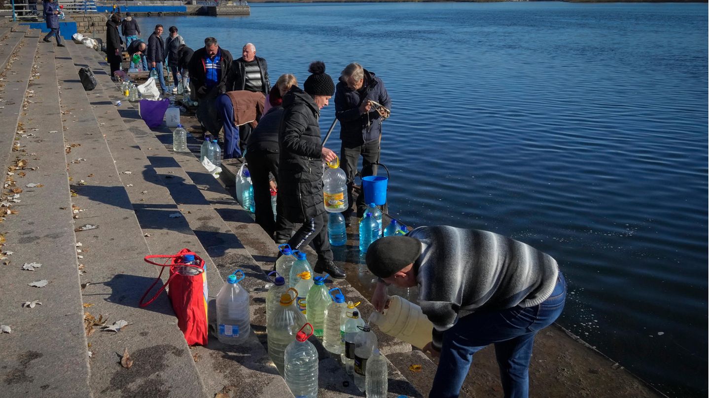 Menschen füllen Wasser aus dem Fluss Dnipro in Kanister