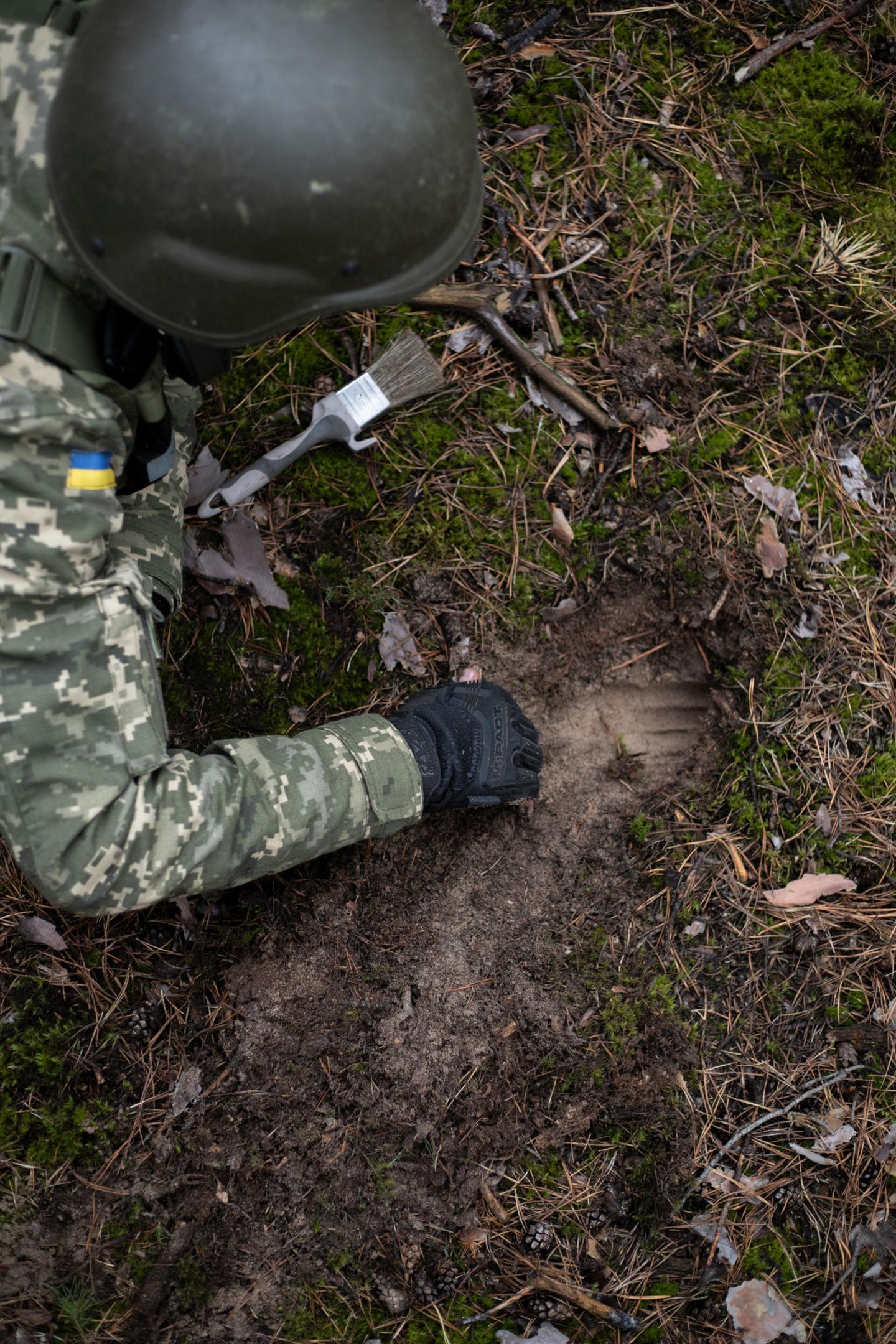 Nachdem der Metalldetektor angeschlagen hat, gräbt ein Ukrainer nach einer Landmine. Neben dem Detektor und einem handelsüblichen Pinsel sind seine wichtigsten Werkzeuge die Hände