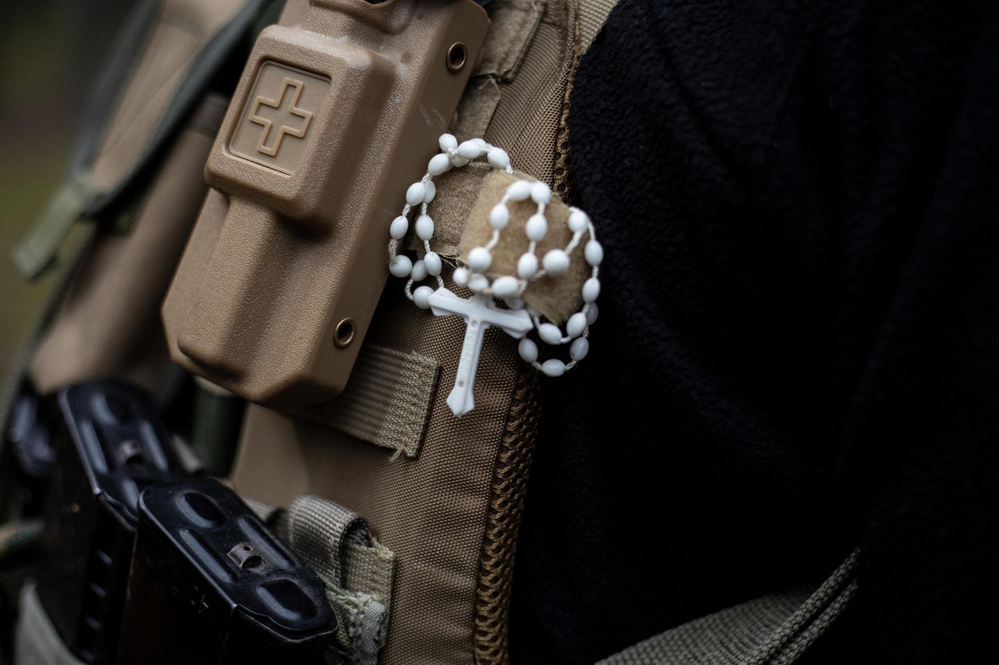 Persönliche Schutzpatronen Ein ukrainischer Soldat trägt ein Kreuz an seiner kugelsicheren Weste. Auch Bänder in den Landesfarben der Ukraine finden sich an den Westen und Gewehren der Soldaten. Häufig bringen die Freiwilligen auch dienstfremde Aufnäher auf den Uniformen an
