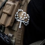 Ein ukrainischer Soldat trägt ein Kreuz an seiner kugelsicheren Weste. Auch Bänder in den Landesfarben der Ukraine finden sich an den Westen und Gewehren der Soldaten. Häufig bringen die Freiwilligen auch dienstfremde Aufnäher auf den Uniformen an