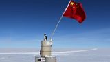 Ein Pinguin sitz bei Dome Argus auf einem Berg aus Fässern