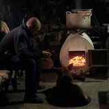 Nothelfer wärmt sich mit Hund an einem Holzofen auf