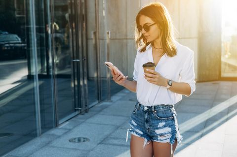 iphone 12 vs. 13: Eine Frau schaut auf ihr iPhone 12 Pro.