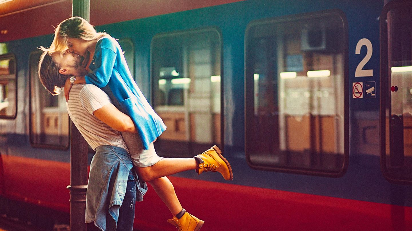 Ein Paar küsst sich am Bahnsteig.