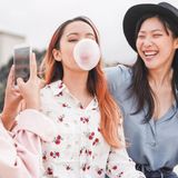 Drei Frauen sitzen zusammen und machen Kaugummi-Blasen.