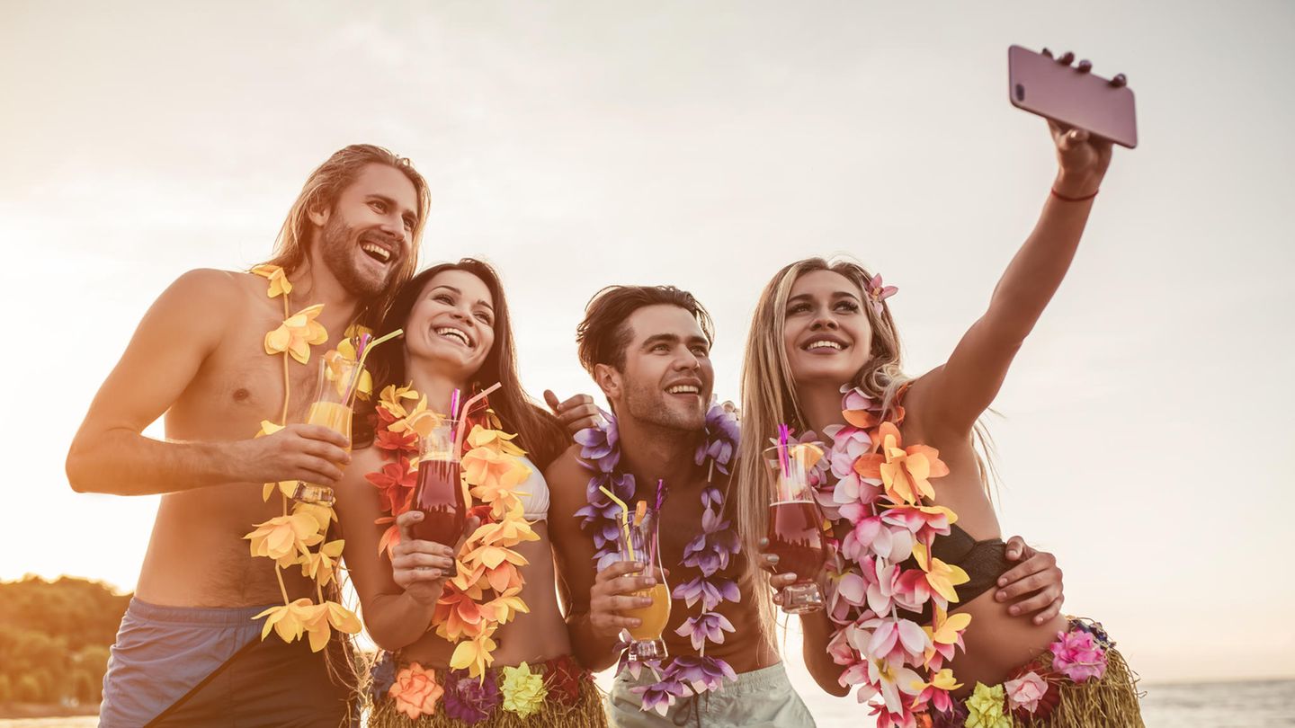 Vier Freunde machen auf Hawaii ein Selfie mit dem Smartphone. Vier Freunde machen auf Hawaii ein Selfie mit dem Smartphone.
