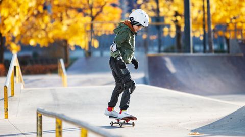 Skateboards für Kinder: Junge übt mit  Schutzausrüstung in Skaterpark