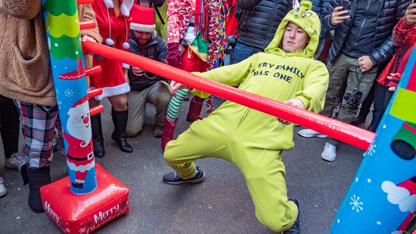 Teilnehmer der SantaCon-Parade tanzen Limbo
