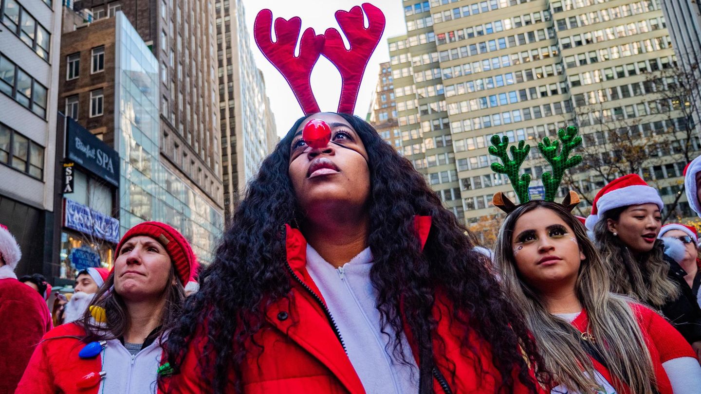 Eine Gruppe junger Frauen mit Rentier-Haarreifen und Weihnachtsmann-Mützen
