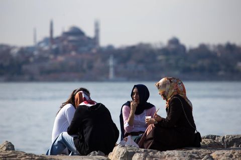 Verschleierte Frauen sitzen in Istanbul am Wasser