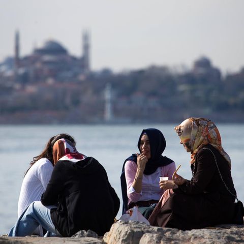 Verschleierte Frauen sitzen in Istanbul am Wasser