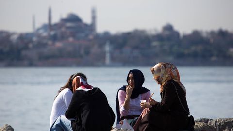 Verschleierte Frauen sitzen in Istanbul am Wasser