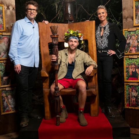 „Dschungelkönig“ 2022 Filip Pavlovic auf dem Thron. Daneben stehen die Moderatoren der 15. Staffel, Daniel Hartwich und Sonja Zietlow.