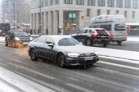 Autos fahren im Winter 2021 bei schneiendem Wetter über eine Straße