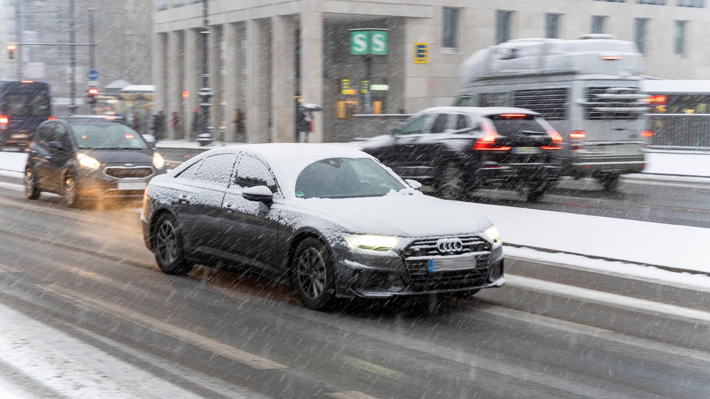 Autos fahren im Winter 2021 bei schneiendem Wetter über eine Straße