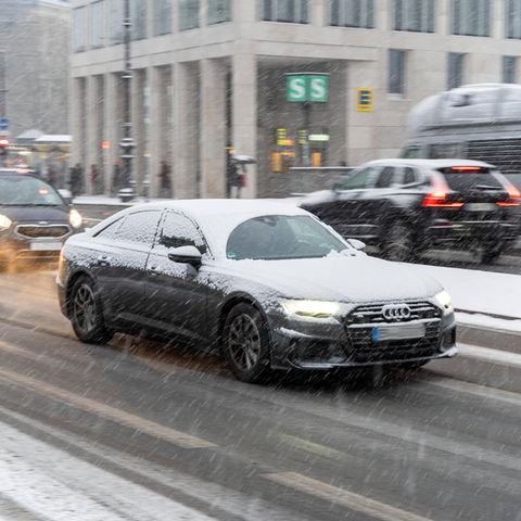 Autos fahren im Winter 2021 bei schneiendem Wetter über eine Straße