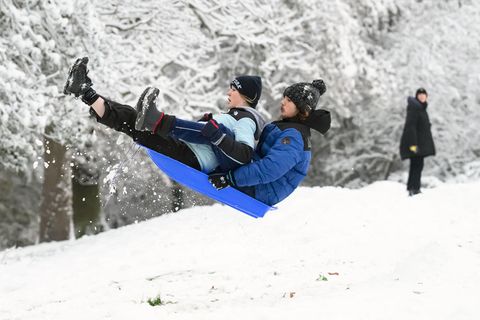 Zwei Londoner nutzen den Schnee in der britischen Hauptstadt für Schlittendspaß im Alexandra Park