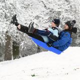 Zwei Londoner nutzen den Schnee in der britischen Hauptstadt für Schlittendspaß im Alexandra Park