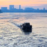 Ein bisschen weiter südöstlich schippert ein Boot bei Sonnenaufgang durch das dünne Eis auf der Hamburger Alster
