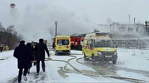 Zwei gelbe Rettungswagen stehen vor einer Industrieanlage, aus der Rauch aufsteigt