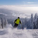 Ein Skifahrer gleitet im tschechischen Adlergebirge einen Hang hinunter ins Tal