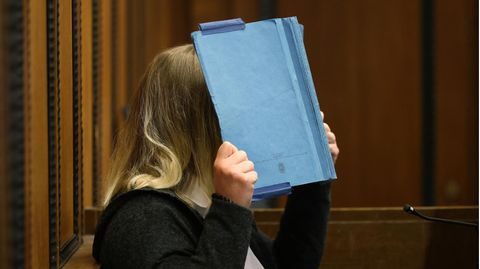Die Angeklagte deckt beim Prozess im Landgericht ihr Gesicht mit einem blauen Ordner ab