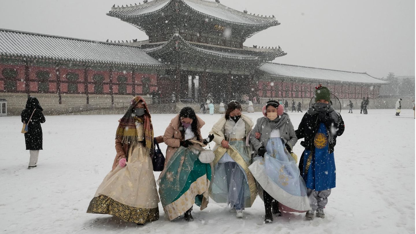 Südkorea, Seoul: Besucher in traditioneller Hanbok-Kleidung gehen im Schnee durch den Gyeongbok-Palast, den wichtigsten Königspalast der Joseon-Dynastie und eines der bekanntesten Wahrzeichen Südkoreas.