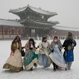 Südkorea, Seoul: Besucher in traditioneller Hanbok-Kleidung gehen im Schnee durch den Gyeongbok-Palast, den wichtigsten Königspalast der Joseon-Dynastie und eines der bekanntesten Wahrzeichen Südkoreas.