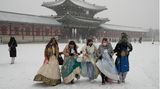 Südkorea, Seoul: Besucher in traditioneller Hanbok-Kleidung gehen im Schnee durch den Gyeongbok-Palast, den wichtigsten Königspalast der Joseon-Dynastie und eines der bekanntesten Wahrzeichen Südkoreas.