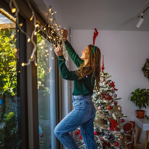 Frau hängt Weihnachtsdeko auf