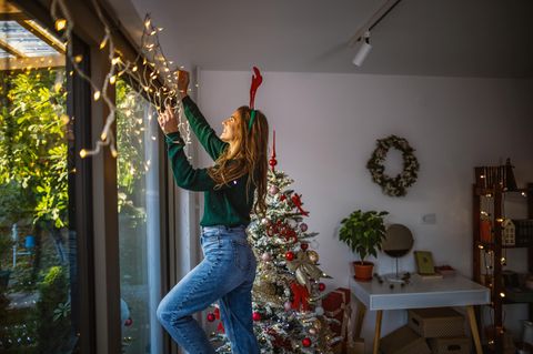 Frau hängt Weihnachtsdeko auf