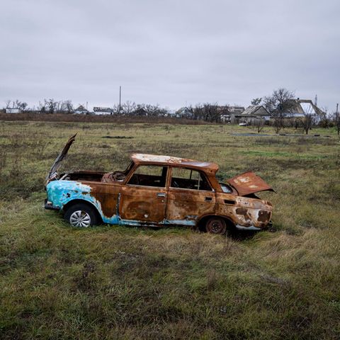 Ein beschossenes Auto steht auf einem Feld bei Cherson