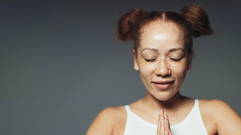 Eine Frau meditiert mit geschlossenen Augen.