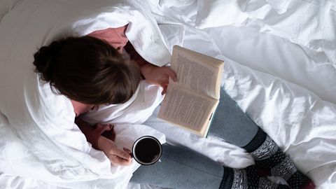 Ein Frau liegt im Bett und liest ein Buch