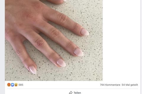 Eine Hand mit künstlichen Acrylnägeln in hellrosa
