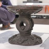 Der Thronhocker des Oba (König) Esigie. Er entstand zwischen 1735 und 1737 und wurde nach dem Vorbild eines Thronhockers aus dem 16. Jahrhundert gegossen. Er stellt das "Weltbild Benins dar. Eine in sich verschlungene Python verbindet die Welt der göttlichen Ordnung der Zivilisation (die Sitzfläche) mit der der Natur (die Basis). Sonne, Mond und Kreuz auf der Sitzfläche stehen für die Schöpfung der kosmischen Ordnung" informiert das ethnologische Museum in Berlin auf seiner Homepage.