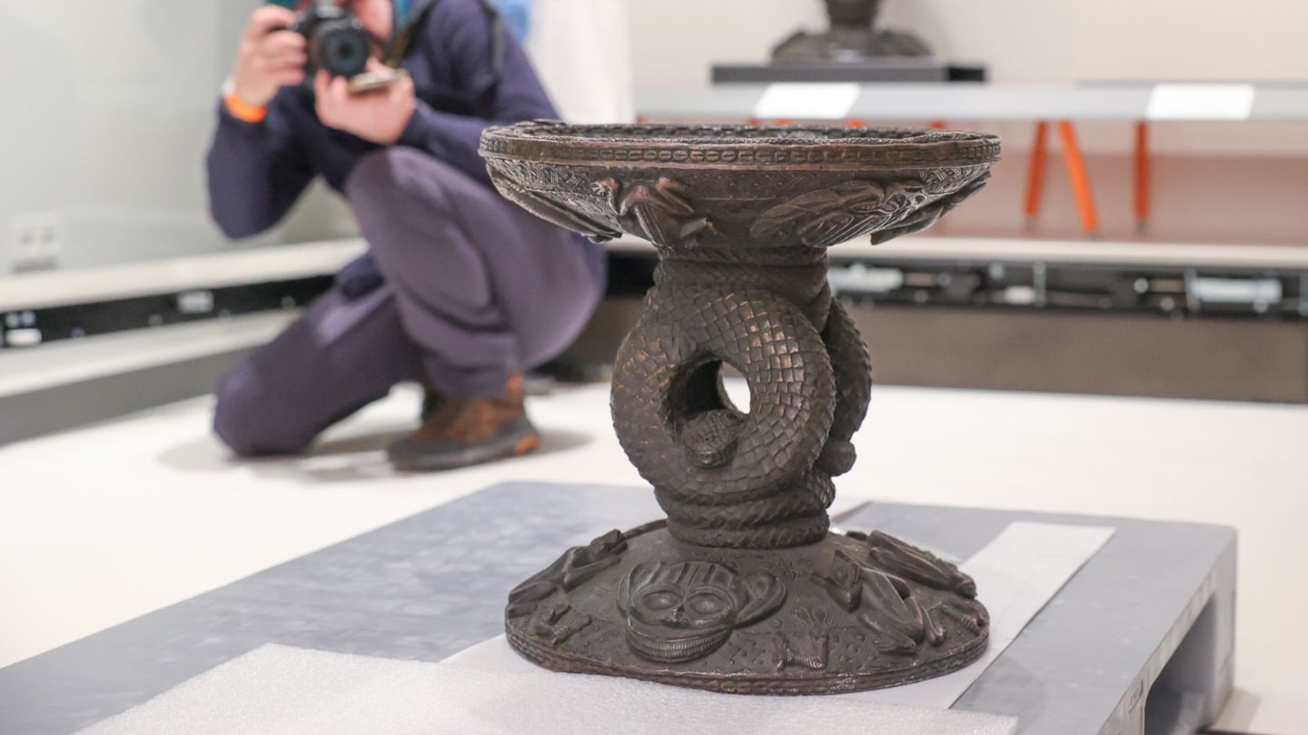 Raubkunst: Der Thronhocker des Oba (König) Esigie. Er entstand zwischen 1735 und 1737 und wurde nach dem Vorbild eines Thronhockers aus dem 16. Jahrhundert gegossen. Er stellt das "Weltbild Benins dar. Eine in sich verschlungene Python verbindet die Welt der göttlichen Ordnung der Zivilisation (die Sitzfläche) mit der der Natur (die Basis). Sonne, Mond und Kreuz auf der Sitzfläche stehen für die Schöpfung der kosmischen Ordnung" informiert das ethnologische Museum in Berlin auf seiner Homepage. Der Thronhocker des Oba (König) Esigie. Er entstand zwischen 1735 und 1737 und wurde nach dem Vorbild eines Thronhockers aus dem 16. Jahrhundert gegossen. Er stellt das "Weltbild Benins dar. Eine in sich verschlungene Python verbindet die Welt der göttlichen Ordnung der Zivilisation (die Sitzfläche) mit der der Natur (die Basis). Sonne, Mond und Kreuz auf der Sitzfläche stehen für die Schöpfung der kosmischen Ordnung" informiert das ethnologische Museum in Berlin auf seiner Homepage.