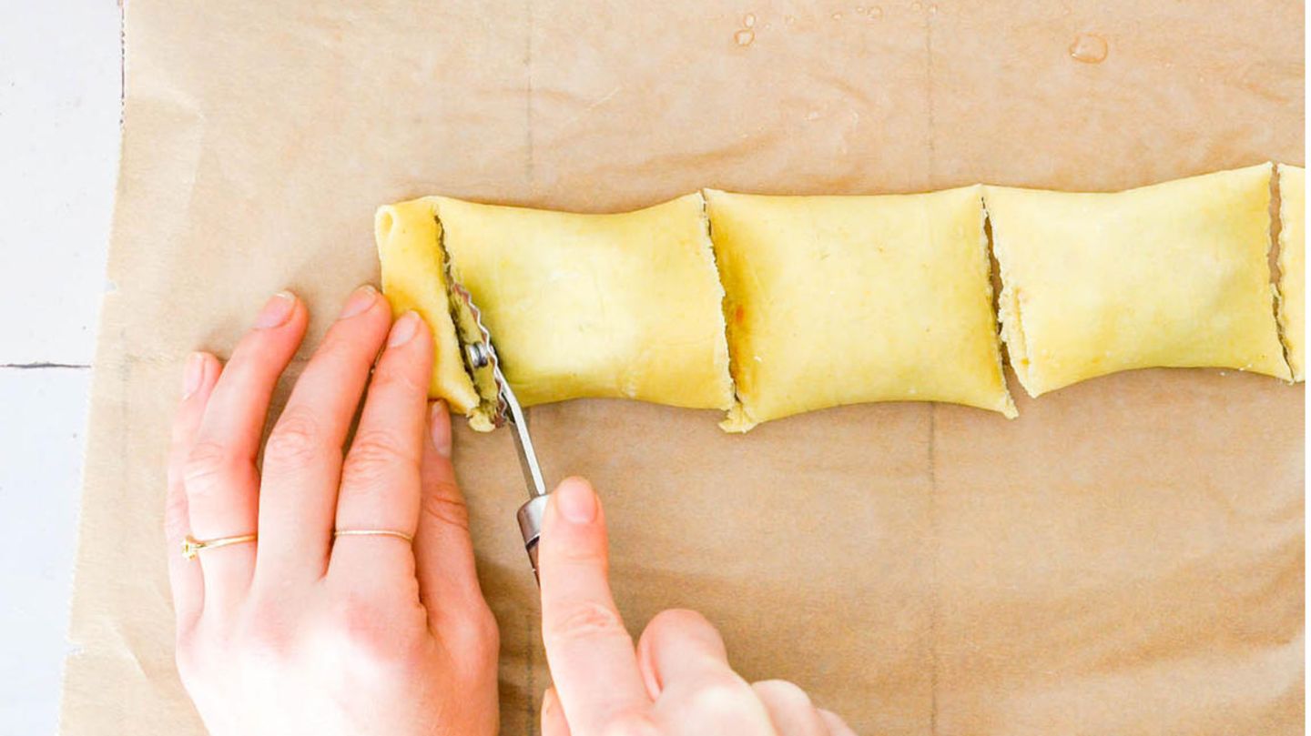 Jetzt den unteren Teil über die Füllung klappen, anschließend den oberen Teil darüberlegen. Mit einem Pfannenwender die Maultaschen abdrücken. Mit einem Teigrädchen auseinanderschneiden und prüfen, ob die Maultaschen gut verschlossen sind.