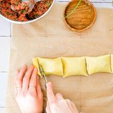 Jetzt den unteren Teil über die Füllung klappen, anschließend den oberen Teil darüberlegen. Mit einem Pfannenwender die Maultaschen abdrücken. Mit einem Teigrädchen auseinanderschneiden und prüfen, ob die Maultaschen gut verschlossen sind.