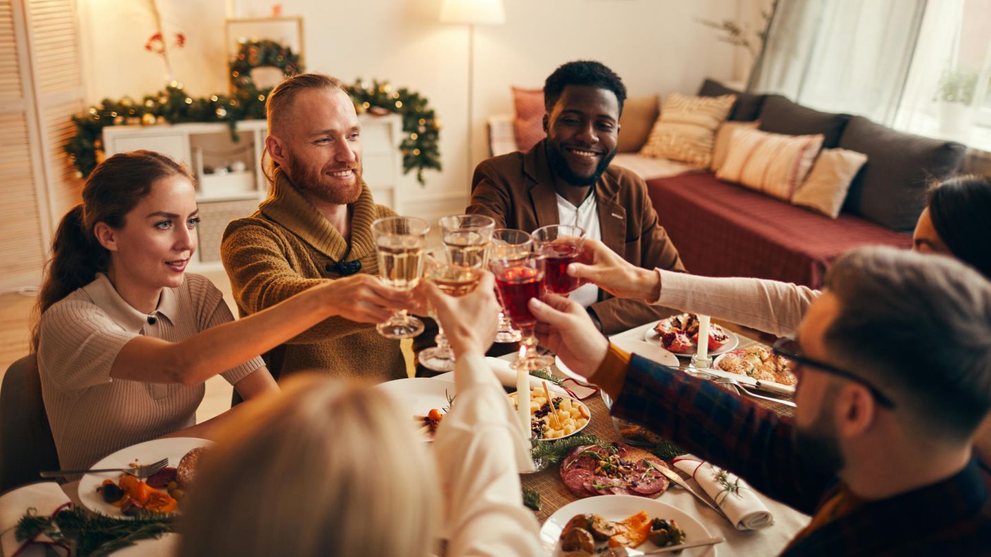 Freunde sitzen versammelt an Weihnachten um den Tisch Freunde sitzen versammelt an Weihnachten um den Tisch