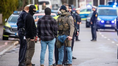 Einsatzkräfte der Polizei stehen nahe eines Tatorts auf der Straße