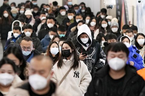 Menschen gehen durch eine U-Bahn-Station in Peking.