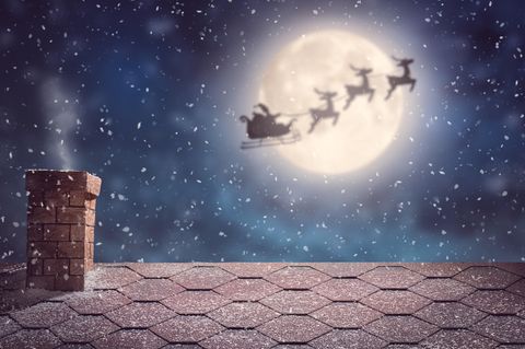 Ein Weihnachtsmann mit seinem Schlitten im Anflug auf ein Haus