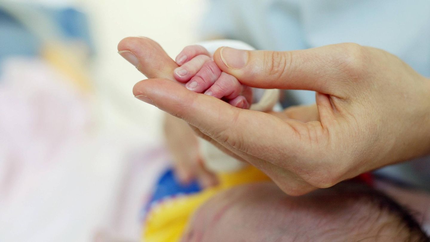 Eine Hand hält die Hand eines Frühchens